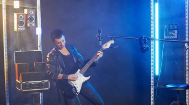 Canlı bir şovda elektro gitarist kadın güçlü ve enerjik bir müzik performansı sergiliyor. Sinirli bir stili ve asi bir grunge havası olan sanatçı müzisyen. Kamera B.