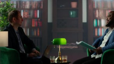 Gizli servis görevlileri viski bardaklarıyla gizli belgeleri inceliyor klasik bir güvenli ev kütüphanesinde buluşuyorlar. Ajanlar gizli görev detaylarına odaklanıyor. Kamera B.