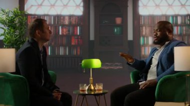 Çeşitli beyefendiler başarılı bir müzakere turundan sonra kadeh tokuşturup kadehlerini kaldırarak toplantıyı iki yaşlı ve zengin üye arasında verimli bir ortaklıkla bitirdiler. Kamera A.