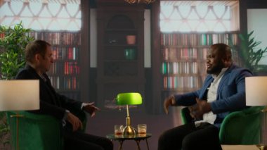 İki çok ırklı işadamı zarif bir kütüphanede viski bardağını paylaşıyor iş stratejilerini tartışıyor ve güven inşa ediyorlar. Lüks ve seçkin sosyal kültürü somutlaştıran kendine güvenen beyefendiler. Kamera A.