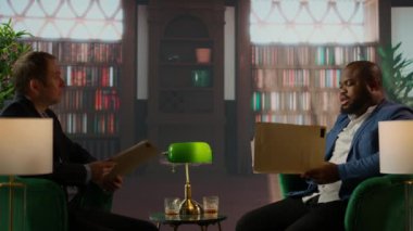 İstihbarat ajanları içki içerken hassas bilgileri analiz eder takım çalışmasını, profesyonelliği ve gizli görev brifinginin özünü tasvir ederler. Büro kütüphanesindeki çok gizli veriler. Kamera A.