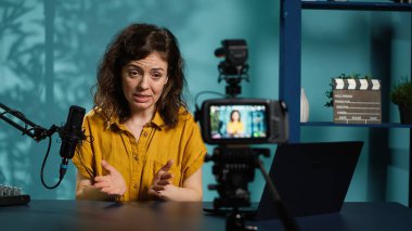 Hevesli internet şovu sunucusu, bugünün video konusunu abonelerle konuşmak için mikrofon kullanarak profesyonel kamerada kayıt düğmesine basıyor. Medya yıldızı yaratıcı vlog, kamera A