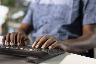 İşçi, ofisteki masaüstü bilgisayarına gelir verilerini giriyor. Masadaki Afrikalı Amerikalı adam şirketin istatistiksel numaralarını yazmaya odaklanmış, son teslim tarihinden önce işi bitirmek için çok çalışıyor.