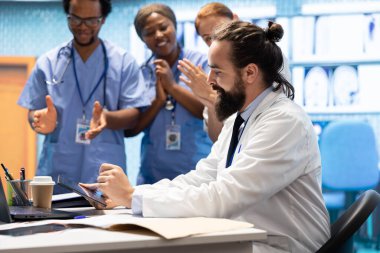Neşeli, kendine güvenen doktorlar ve hemşireler teşhis için doğru tedavi planını buluyorlar. Yetenekli sağlık sektörü çalışanları. Sağlık personeli gülümseyip el çırpıyor, dolapta iyi haberler var..