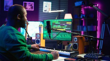 Şarkı sözü yazarı, kendi stüdyosunda şarkı sözleri ve harmonik öğeler yazmak için notlar alıyor. Yazılım ve akustik mühendisliği üzerine yazılar yazmadan önce. Kamera B.