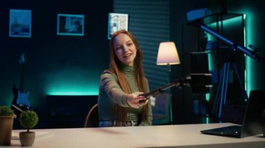 İçerik yaratıcısının bulanık arka planda film odası turunda kullandığı akıllı telefona odaklan. Seyircilere video sunumu yapan genç şovmenlerin kullandığı cep telefonunu kapat, kamera B