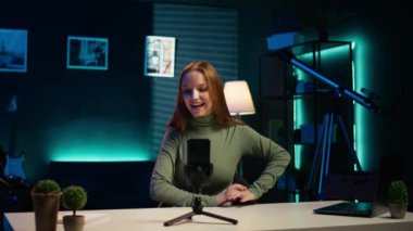 Genç kız çevrimiçi hayranları için içeriği çekmek için akıllı telefon özçekim kamerası kullanıyor ve Z jenerasyonu konuları hakkında konuşuyor. Cep telefonu ve kamera B ile internet kanalı için vlog kaydeden neşeli kişi