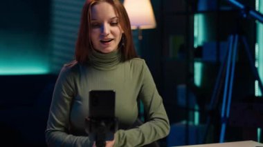 Genç içerik yaratıcısı akıllı telefonlu giriş videosu, el sallama, izleyicileri kanala üye olmaya davet ediyor. Medya yıldızı kendini izleyicilerle, kamera A ile bağlantı kurarken görüntülemek için cep telefonu kullanıyor.