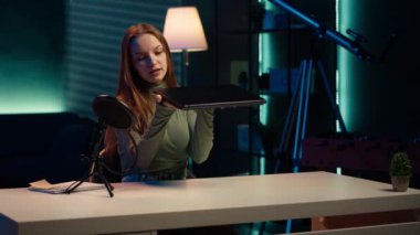 Marka sponsorluğundaki videodan canlı bir dizüstü bilgisayar sunan genç şovmen, izleyicileri onu satın almaya teşvik ediyor. Kız, stüdyo ve kamera A 'daki izleyicilere ince not defteri tanıtarak pazarlamayı etkiliyor.