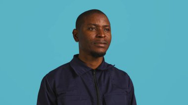 Headshot portrait of african american security agent isolated against colored studio background. Close up shot of guardian securing assigned post standing over studio backdrop, camera B clipart