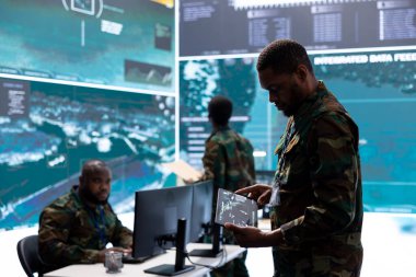 Veri işleme, gerçek zamanlı gözetleme ve ulusal savunma ve stratejik operasyonlar için gerekli güvenlik protokollerini entegre etme üzerinde çalışan bir kontrol merkezinde çalışan askeri personel..