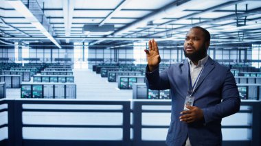 System administrator looking at holograms in data center, monitoring equipment. Employee in server farm interacting with futuristic augmented reality AI visualization, camera B clipart