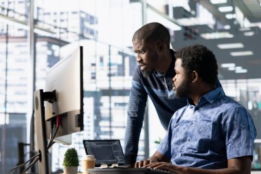 Bilgisayar masasındaki veri mühendisliği personeli makine öğrenme algoritmaları geliştiriyor. Afrika kökenli Amerikan ekibi görevleri çözüyor, bilgisayar kullanarak büyük ölçekli derin öğrenme modelleri eğitiyorlar.