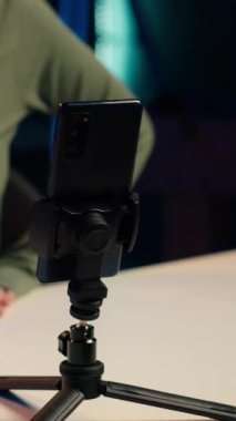 Etkilenen kişi tarafından çevrimiçi hayranları için içeriği filme almak için kullanılan cep telefonuna dikey video odağı, Z jenerasyonu konuları hakkında konuşuyor. İçerik oluşturucu kayıtları üç ayaklı cep telefonlu internet kanalı için vlog