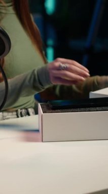 Dikey video Gen Z içerik yaratıcısı yeni çıkan akıllı telefonun teknoloji değerlendirmesini kaydediyor, paketleri açıyor ve izleyicilere özelliklerini sunuyor. İnternet yıldızı stüdyodaki hayranlarına cep telefonunu gösteriyor