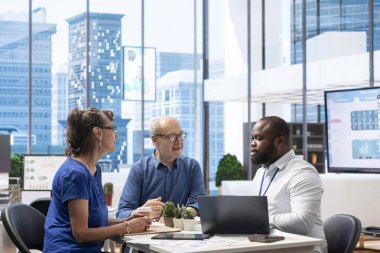 Emeklilik ve emeklilik planlama konusunda danışmanlık yapan kıdemli kişiler, geleceği hayat sigortası ve tasarruflarla güvence altına alıyorlar. Modern ofiste finansal seçeneklerini gözden geçiriyorlar..