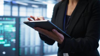 Bilgisayar bilimcisi dijital cihaz kullanarak ileri teknoloji ile veri merkezini yönetiyor. Sunucu odasında tablet, kamera B ile veri merkezi donanımını optimize eden kişinin yakın plan görüntüsü