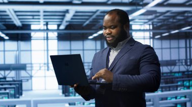 Veri merkezinde dizüstü bilgisayarda yazan programcı, hata kontrol araçları çalıştırıyor. Bilgi İşlem uzmanı sunucu odasında dijital aygıt, kamera A kullanarak sondaj performansını etkileyen ağ sorunları arıyor