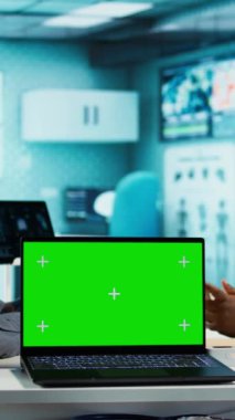 Dikey video Afrikalı Amerikalı genç adam doktoruna mankenin yanındaki tavsiyeyi soruyor, sağlık kontrolünde tıbbi kayıtları birlikte analiz ediyor. Hasta bir hastayla doktor toplantısı. Kamera B.