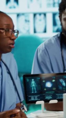 Bir toplantı sırasında hasta sağlık kayıtlarını tartışan dikey video uzmanları, iyi donanımlı bir doktor ofisinde modern tanı araçları ve teknolojiden faydalanıyorlar. Asistanlar birlikte çalışır