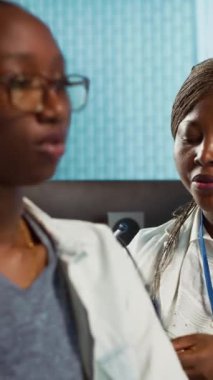 Dikey video pratisyeni, hastaya hastalık konusunda danışmak için steteskop kullanır. Akciğerlerin ve kalp atışlarının normal çalışmasını sağlar. Sağlık kontrolünde solunum sorunu olan Afrikalı Amerikalı kız.