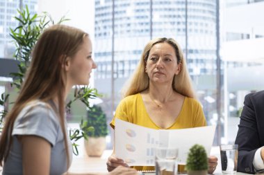 Clients looking over statistical charts given by financial advisor analyzing market trends and providing informed recommendations to optimize their income. Women reading investment plan in office clipart