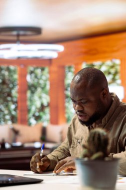 Girişimci not alıyor ve ofisteki iş analizlerini yönetiyor, bir dizüstü bilgisayardaki ekonomik eğilimleri analiz ediyor. Serbest çalışan danışman uzaktan çalışmanın etkinliğini gösteriyor..