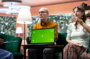Hemşire, üst düzey hastalarına laptopta yeşil ekranın yanında profesyonel tavsiyeler veriyor. Sosyal bir ziyaret sırasında yaşlı çifte danışmanlık yapıyor. Tıbbi asistan destek ve ilaç öneriyor.
