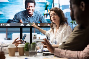 Genel müdür, kurum hedeflerine ulaşmak için en son proje güncellemelerini tartışmak üzere bir toplantı odasında uzaktan video bağlantısı üzerinden personelini kontrol ediyor. Profesyonel çalışma ekibi..