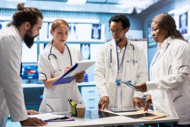 Kabinede test sonuçları ve hastane kayıtlarını karşılaştıran uzman doktorlar, hastalık önleme konusunda danışmanlık yapıyorlar. Bölüm toplantısında uzmanlıklarını paylaşan çok sayıda doktor.
