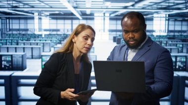 Veri merkezindeki sistem yöneticileri dizüstü ve tablet kullanarak sunucu işlemlerini denetliyor. Sunucu merkezinde iş arkadaşlarının beyin fırtınası yapması, optimal performans ve veri bütünlüğü sağlanması, kamera B