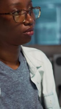 Dikey video Afrikalı Amerikalı kız ultraviyole ışınlı iyi bir güneş kremi kalkanı soruyor. Doktor cilt bakımı için spf 50 ile kozmetik öneriyor. Doktor ve hasta dermatoloji kontrolünde. Kamera.
