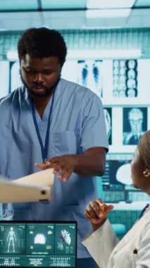 Dikey video Afrikalı Amerikalı doktor bir kızla sağlık sorunları hakkında konuşuyor, tedavi ve önleme için tıbbi verileri ve teknolojik ekipmanları kullanıyor. Klinik muayenesi. Kamera A.