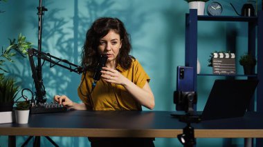 İçerik yaratıcısı hayranları için ASMR tarzı bir video hazırlıyor, evinde çekim yapıyor. Profesyonel mikrofonu kullanarak çevrimiçi program sunucusu, izleyicileri uyutuyor ve uyutuyor, kamera B