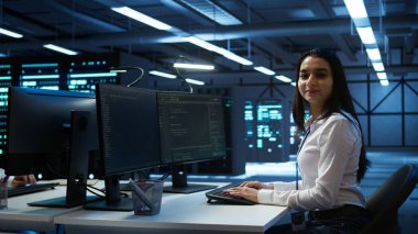 Veri merkezini denetleyen gülümseyen mühendisin portresi, sistemin ağ oluşturma görevlerini yerine getirdiğinden emin olmak için geliştirmeler ve güncellemeler yapıyor. Neşeli sunucu odası çalışanı ağ trafiğini takip ediyor, kamera B