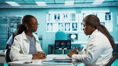 Bir hastayla tıbbi verileri inceleyen kadın pratisyen, sağlığa odaklı uzman istişare sırasında etkileşimi ve güveni teşvik eden. Afrikalı Amerikalı kız tavsiye istiyor. Kamera B.