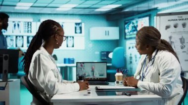 Doktor, bir hastayla video konferansı için uzman doktoru arıyor. İkinci bir görüş için tele sağlık danışmanlığı yapıyor. Klinikte yüksek teknolojili ekipman kullanan tıbbi personel. Kamera B.