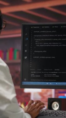 Dikey video yönetimi yapay zeka sinir ağları üzerinde bakım yapıyor bilgisayarlı model, müzik dinliyor. Kulaklık takan teknik destek uzmanı yapay zeka sistemlerini kontrol ediyor, kamera B