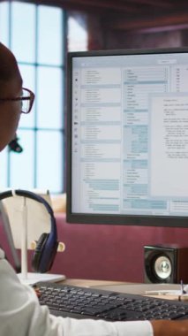 Merkez ofisteki dikey video mühendisi UI 'ye bilgisayar monitöründe bakar, programlama kodunu yazar ve çalıştırır. IT çalışanının kodlama uygulamasını kullanarak modern kodları yazarken ve test ederken çekilen görüntüsü