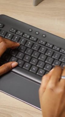 Ofis masasında kahve fincanının yanında bilgisayarda yazan dikey video görüntüsü. Yakın çekim. Uzaktan kumandalı apartman çalışanı bilgisayarın çevre tuşlarına basıyor, veri giriyor, kamera A