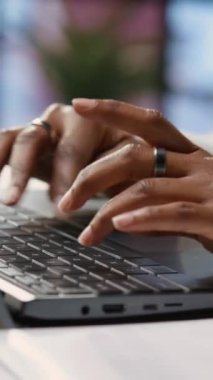 Ofiste masa başında oturup dizüstü bilgisayarda klavye çalan dikey video Freelancer. Çevrimiçi müşteri ilişkilerinde elektronik aygıt kullanarak uzaktan çalışan işçiyi kapat, sorulara cevap ver