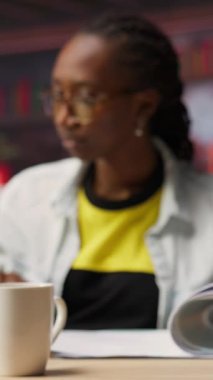 Vergi formlarını inceleyen, dizüstü bilgisayardaki raporları okuyan ve bilgi yazan bir muhasebe görevlisi. Uzaktan çalışan muhasebeci mali işleri uzaktan yönetiyor, notlar alıyor, kamera B