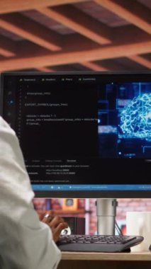 Dikey video yönetimi yapay zeka sinir ağları üzerinde bakım yapıyor bilgisayarlı model, müzik dinliyor. Kulaklık takan teknik destek uzmanı yapay zeka sistemlerini ve kamera A 'yı kontrol ediyor.