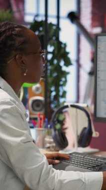 Merkez ofisteki dikey video mühendisi UI 'ye bilgisayar monitöründe bakar, programlama kodunu yazar ve çalıştırır. IT çalışanının kodlama uygulamasını kullanarak modern kodları yazarken ve test ederken çekilen görüntüsü