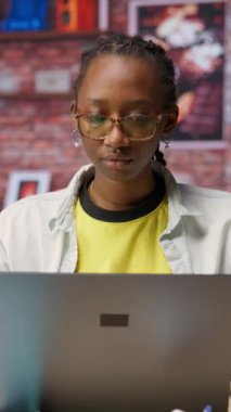 E-posta yazmak için ev bilgisayarını kullanan mutlu bir tele-işçinin dikey video portresi. Not defterine yazan neşeli uzaktan çalışan, bitirilmiş proje evraklarını teslim etmek için dokümanlar düzenleyen