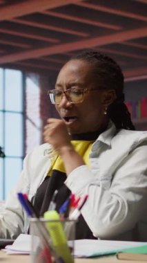 Merkez ofisteki dikey video teknisyeni dizüstü bilgisayarla çalışırken kendini yorgun hissedip esniyor. Yeşilleşmiş Afro-Amerikan uzaktan kumandalı çalışanı kaslarını gevşetiyor, defterdeki görevleri çözüyor.