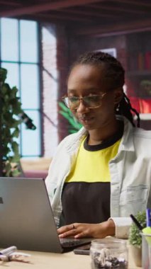 Evde çalışmaya başlayan dikey video işçisi, masadaki verileri analiz etmek için laptop açıyor, analitik raporlar derliyor. Uzak çalışan görevlere başlıyor, dizüstü bilgisayar aygıtı kullanıyor, bilgi yazıyor