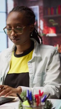 Dikey video teknisyeni masadaki verileri analiz ediyor ve evrak işlerini inceliyor, analitik raporları derliyor. Şirket bilgilerini yüklemek için dizüstü bilgisayar kullanan uzaktan çalışan belgeleri kontrol ediyor