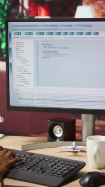 Ana ofisteki dikey video kadın bilgisayar ekranında UI 'ye bakıyor, programlama kodunu yazıyor ve çalıştırıyor. Kullanılan kodlama uygulaması UI yazılım ve test kodu modern apartman, kamera A