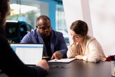 Sergi salonundaki müşteriler yeni bir araba almaya karar verdikten sonra kredi başvurusu ve evrak işlerini tamamlıyorlar. Satış elemanı müşterilerle finansman seçeneklerini tartışıyor